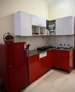 a kitchen with red cabinets and a red refrigerator at Calm Corner in Panchkula