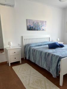 a white bedroom with a bed and a night stand at Rosanna House in Bombarde Beach in Alghero