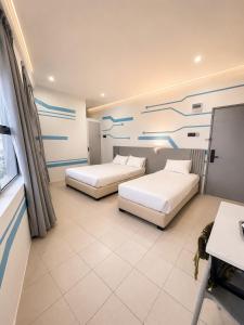 a hotel room with two beds and a painting on the wall at One Stop Hotel Ipoh in Ipoh