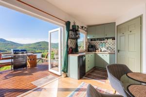 a kitchen with green cabinets and a large sliding glass door at Sherpa Pihenőház in Nagymaros