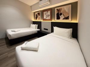 two beds in a hotel room with white sheets at Tropics Eight Suites in George Town