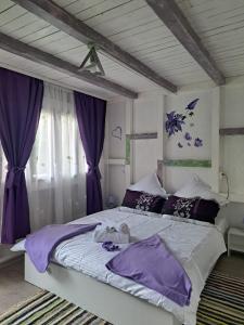 a bedroom with a large bed with purple sheets at Căsuța Vesela in Cernişoara