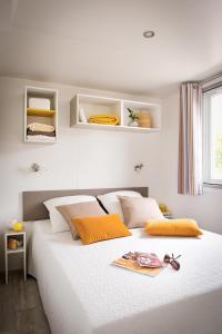 sypialnia z dużym białym łóżkiem z pomarańczowymi poduszkami w obiekcie Giannella Camping w mieście Orbetello