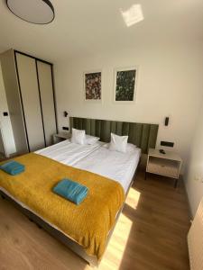 a bedroom with a large bed with a yellow blanket at SKALNY apartamenty, pokoje - Ogród, Spokój i Natura in Ogrodzieniec