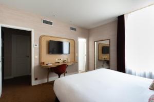 a bedroom with a bed and a desk and a tv at Chapeau Rouge par William Frachot - Hôtel Espace Bien-être & Restaurant étoilé in Dijon