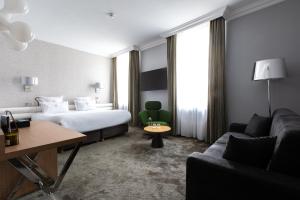 a hotel room with a bed and a couch at Chapeau Rouge par William Frachot - Hôtel Espace Bien-être & Restaurant étoilé in Dijon