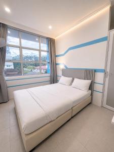 a bedroom with a large white bed with a window at One Stop Hotel Ipoh in Ipoh