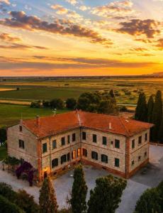 an aerial view of a building with a sunset in the background at Fattoria Barca Colonna in Orbetello