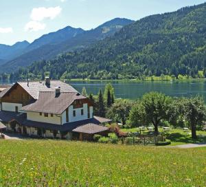a large house with a lake and mountains in the background at Ferienhof Obergasser und Bergblick in Weissensee