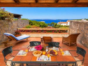 a table with food and flowers on a patio at Amazing Sea View Terrace A with Pool 70m from the Beach in Baja Sardinia