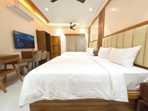 a bedroom with a large white bed and a desk at PSR Coral Resorts, 800m Away from Rameswaram Temple in Rāmeswaram