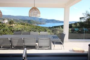a dining room table with chairs and a view of the water at Villa d exception piscine privée 200m2 10 pers RESTONICA Les Terrasses de Ruppione in Pietrosella