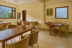 a dining room with tables and chairs and windows at Hotel The Winterline - Best Selling Property in Kasol 2025-26 in Kasol