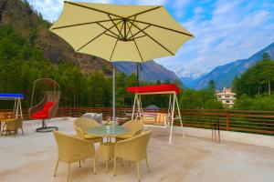 a patio with a table and chairs and an umbrella at Hotel The Winterline - Best Selling Property in Kasol 2025-26 in Kasol +26 photos