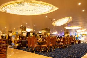 ein Festsaal mit Tischen und Stühlen und einem Kronleuchter in der Unterkunft Hotel Harmony Inn in Meerut