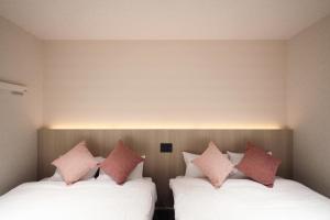 two beds in a room with pink pillows on them at MOMIJI TERRACE Hiroshima in Hiroshima