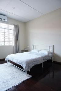 a white bedroom with a bed and a window at Kim_Homestay in Tawau