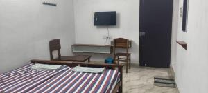 a room with a bed and two chairs and a tv at Santha Residency in Ambātturai