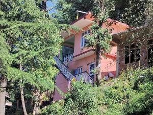 a pink building with stairs in the middle of trees at Tree Valley Homestay Chail in Chail