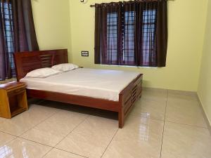 a bedroom with a bed and two windows at Coz Rooms in Varkala