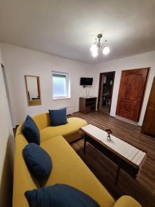 a living room with a yellow couch and a table at Aranymoha Vendégház in Szőce