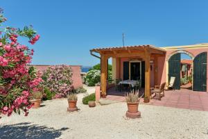 a patio with a table and chairs and flowers at Salina Holiday Home in Calasetta