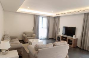 a living room with couches and a flat screen tv at Farms Fintas - Family Only in Kuwait