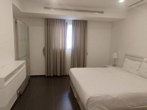 a bedroom with a large white bed and a window at Farms Fintas - Family Only in Kuwait