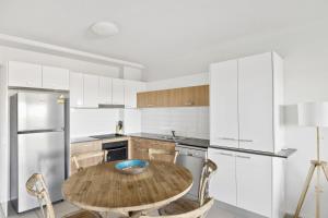 a kitchen with a wooden table and white appliances at Saltwater on the Peninsula in Kawana Waters