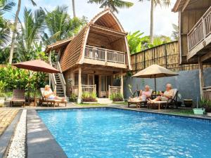 a group of people sitting around a swimming pool at a resort at Brady's BED & breakfast Ubud in Ubud