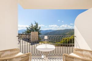 a balcony with a table and chairs and a view of mountains at Marinaio di foresta Bedroom in Baunei