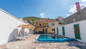 a swimming pool with chairs and an umbrella next to a house at Villa UpTown in Mostar