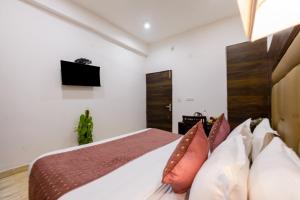 a bedroom with a bed with a television on the wall at Hotel Kiara - Near Delhi Airport in New Delhi