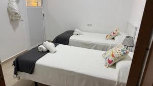 two beds in a room with white walls at Ventana al mar in Tangier