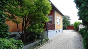 a house with a tree next to a brick sidewalk at Borostyán Nyaralóház Balatonboglár in Balatonboglár