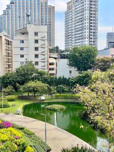 a park with a pond in a city with tall buildings at De Chalet in Bangkok