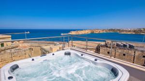a hot tub on a balcony with the ocean in the background at Valletta Luxury 4-Bedroom Duplex with Stunning Sea Views Private Terrace and Jacuzzi in Valletta