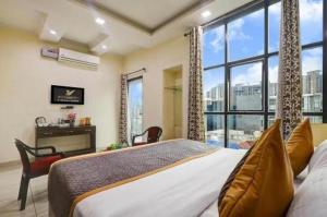 a bedroom with a bed and a large window at Hotel Vibe Blue Sec 70, Near Kailash Hospital & Sec 61 -52 Metro in Noida +23 photos