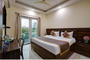 a bedroom with a bed and a desk and a window at Hotel Vibe Blue Sec 70, Near Kailash Hospital & Sec 61 -52 Metro in Noida