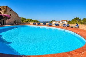 a large blue swimming pool on a brick patio at Amazing Sea View Terrace A with Pool 70m from the Beach in Baja Sardinia