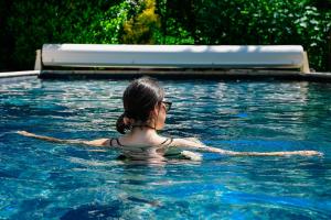 a woman in a swimming pool in the water at Logis Hôtel La Cascade - Lyon Nord in Saint-Genis-les-Ollières