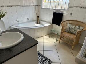 ein Badezimmer mit Badewanne, Waschbecken und Stuhl in der Unterkunft Koi liv-Inn Bedfordview ll Modern Guest House Near OR Tambo in Bedfordview