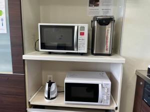 a microwave and a coffee maker on a shelf at Hotel Morimotoya 板野店 in Kamiita