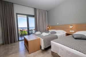 a hotel room with two beds and a balcony at Filoxenia Studios in Afitos