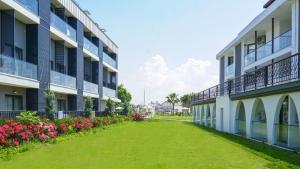 an apartment building with a green yard next to flowers at Side Square Hotel Adults Only in Side +19 photos