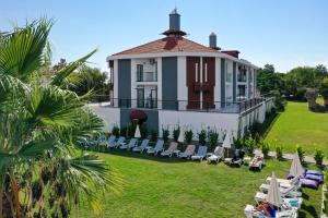 a villa with a lawn and chairs in front of it at Side Square Hotel Adults Only in Side