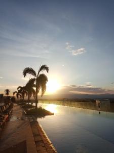 a pool with a palm tree and the sunset at Mactan Newtown Deluxe 8 Boulevard Ocean View in Lapu Lapu City
