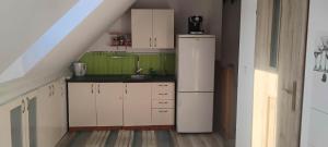 a small kitchen with white cabinets and a refrigerator at Lipowy domek Mazury in Piecki +18 photos