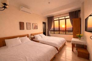 a hotel room with two beds and a window at Chichi Inn Hotel CoTo in Đảo Cô Tô