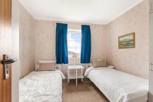 two beds in a room with blue curtains at Reine Panorama in Reine